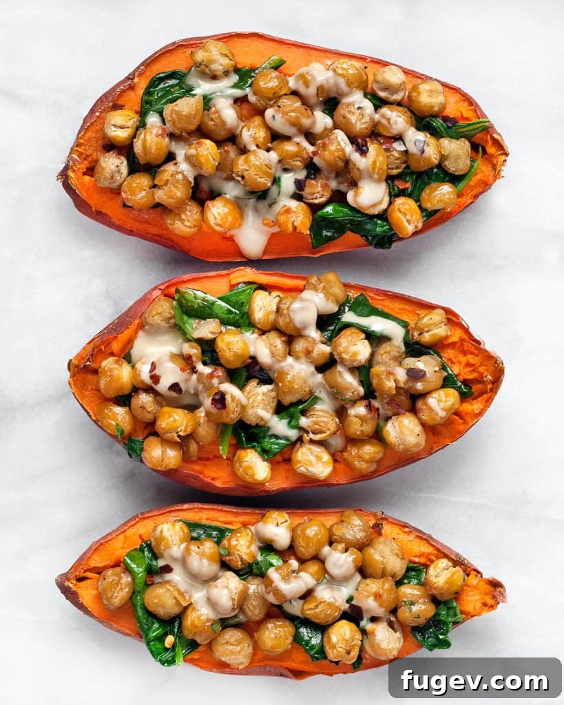 Savory Chickpea and Spinach Stuffed Sweet Potatoes 7 Three perfectly baked sweet potato halves, generously topped with crispy roasted chickpeas, vibrant sautéed spinach, and a smooth tahini drizzle, ready for a healthy meal.