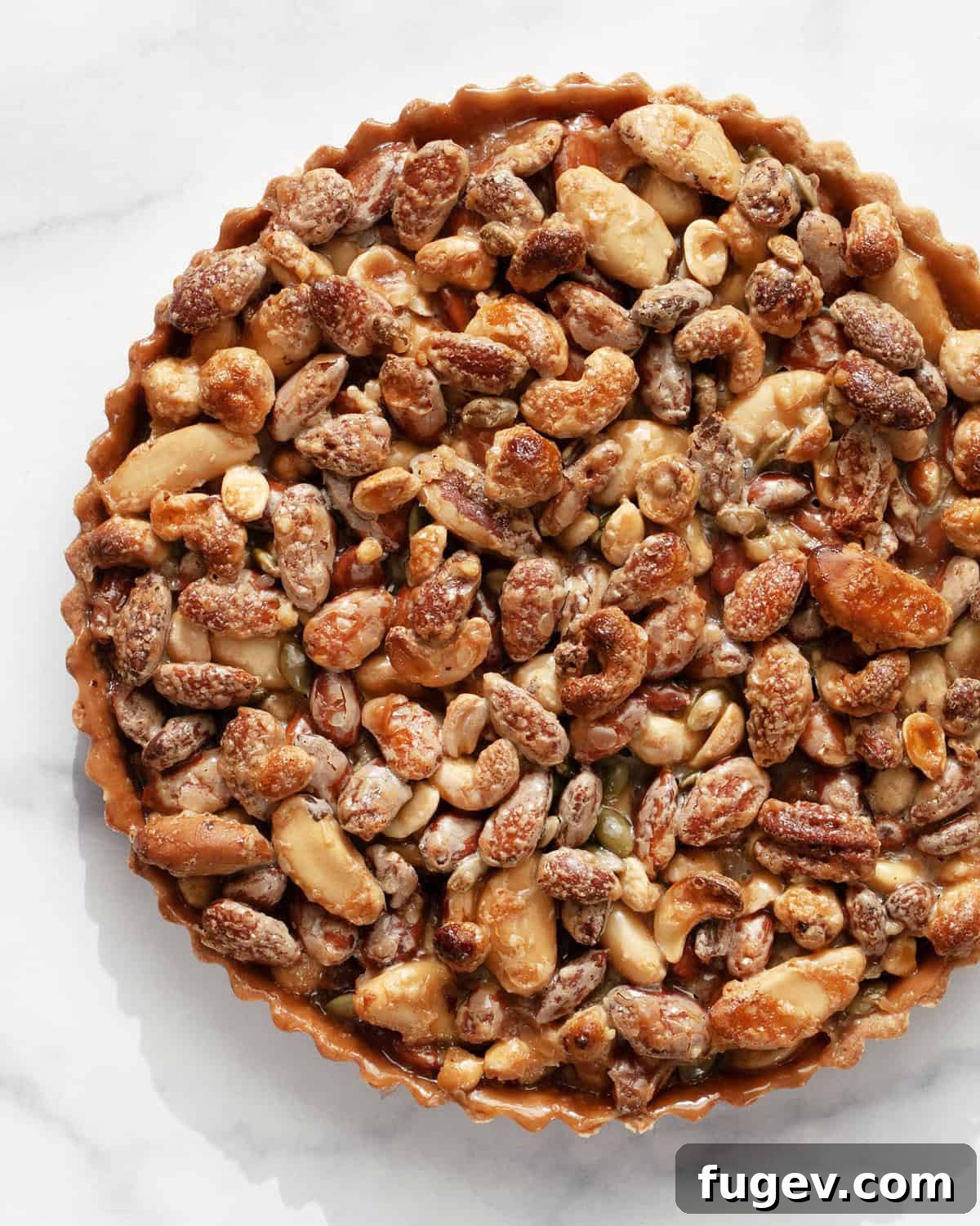 Caramelized Nut Tart 2 A glistening caramel mixed nut tart, adorned with various nuts, resting on a sophisticated marble surface, ready to be served.