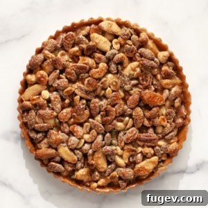A beautifully crafted caramel mixed nut tart, showcasing its golden crust and rich, glossy filling with mixed nuts, ready to be enjoyed.
