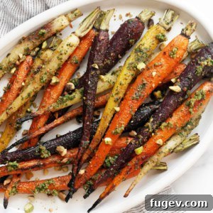 Roasted Rainbow Carrots and Their Green Crown Pesto 8 Close-up of roasted rainbow carrots with bright green carrot top pesto on a serving plate.