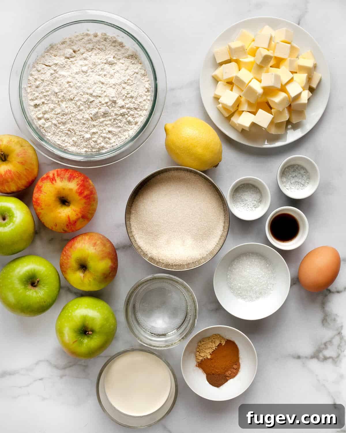 Salted Caramel Apple Crumble Pie 4 A flat lay of all the essential ingredients for making salted caramel apple pie, including apples, flour, sugar, butter, spices, and lemon.