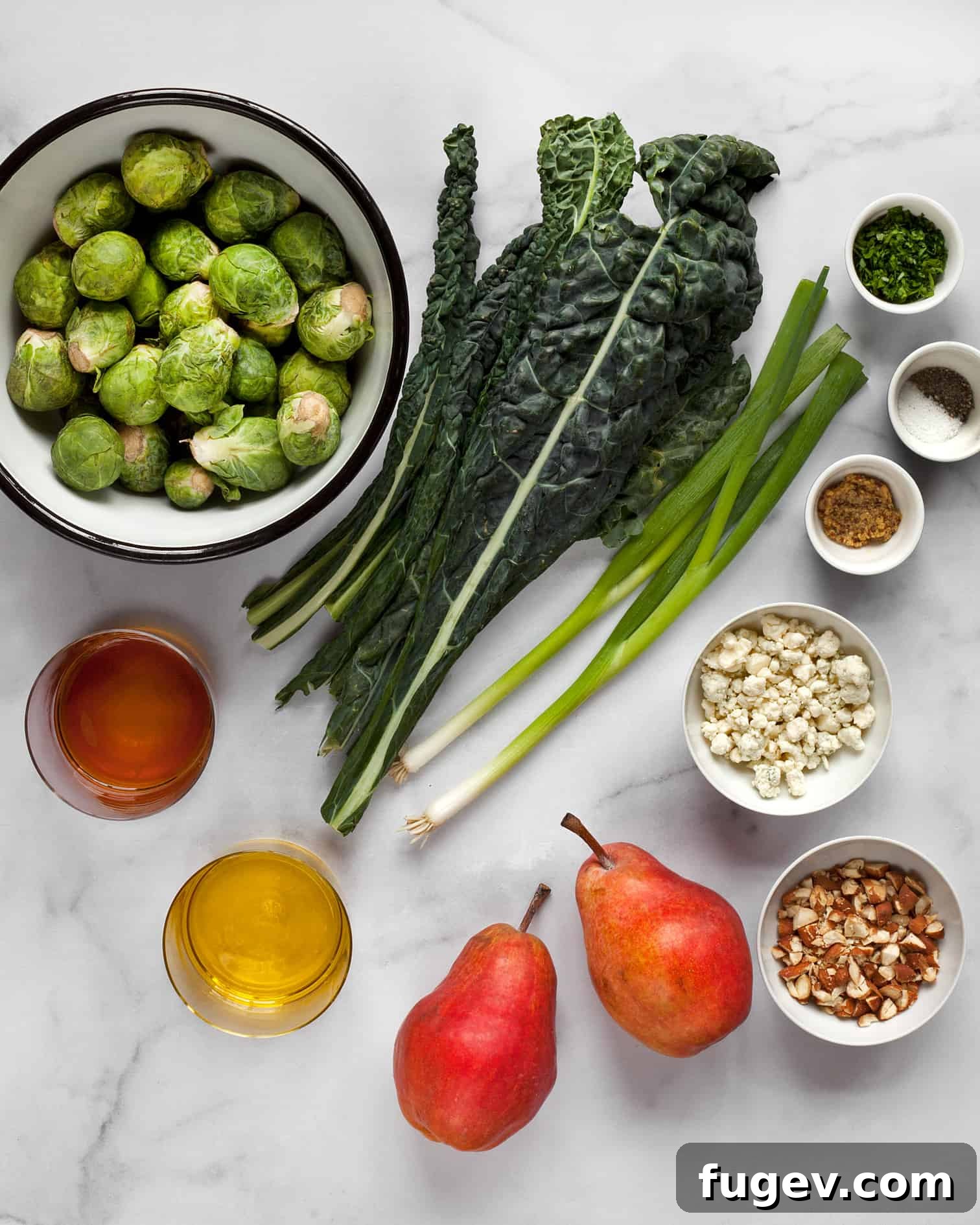 Sweet Pear and Shaved Brussels Kale Salad 3 A flat lay image displaying all the fresh ingredients for a healthy kale and brussels sprout salad, including vibrant green kale, whole brussels sprouts, red pears, sliced scallions, raw almonds, and blue cheese crumbles.