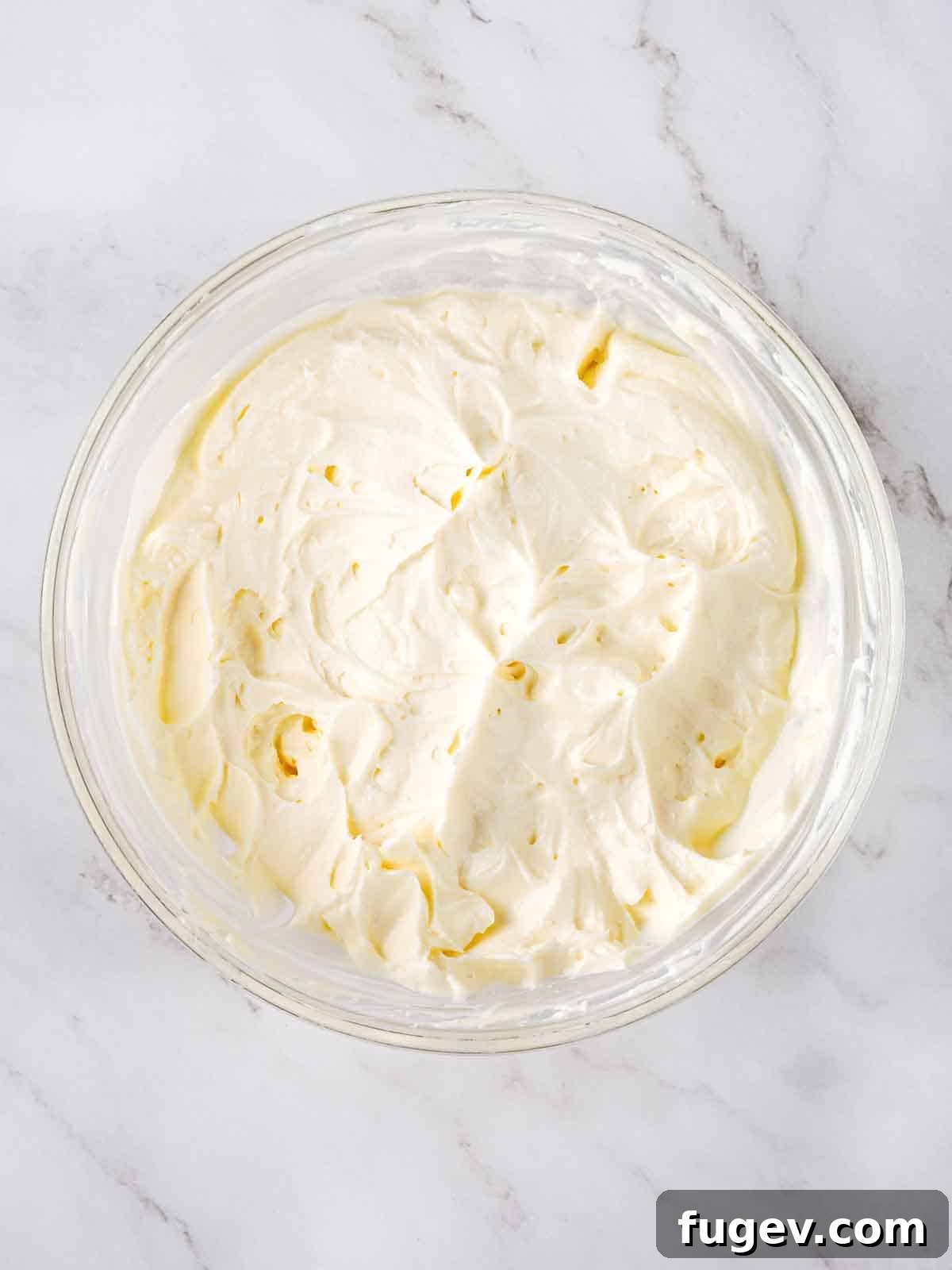 Lush Cream Cheese Buttercream 2 Fluffy cream cheese frosting in a clear glass bowl, ready to be used.
