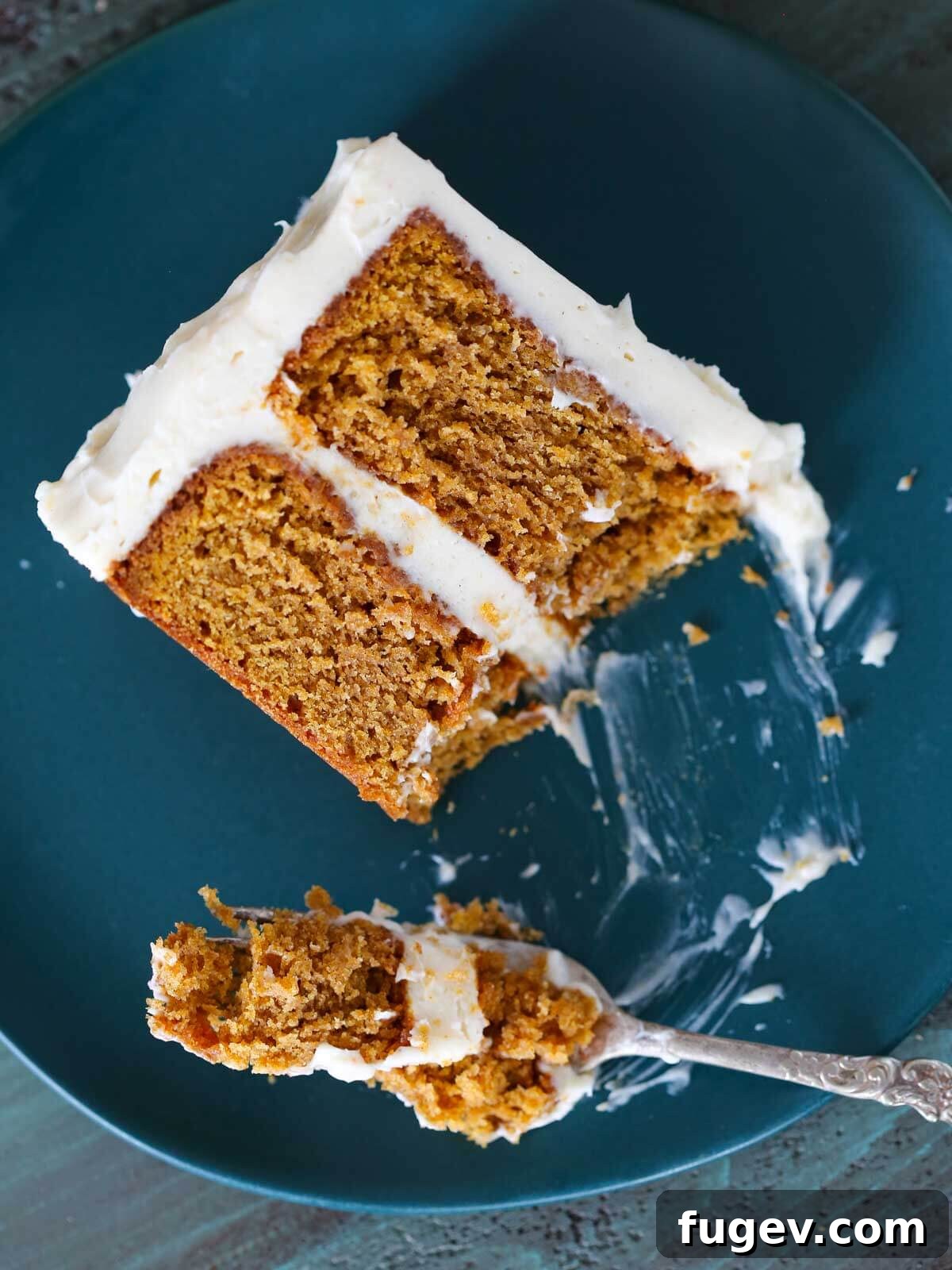 Lush Cream Cheese Buttercream 11 A fork taking a bite of pumpkin cake from a plated slice.