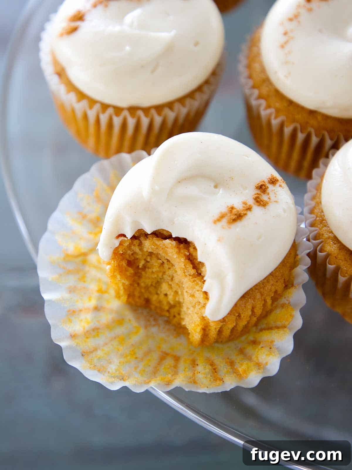 Lush Cream Cheese Buttercream 12 Spiced cream cheese buttercream on pumpkin cupcakes arranged on a cake stand.