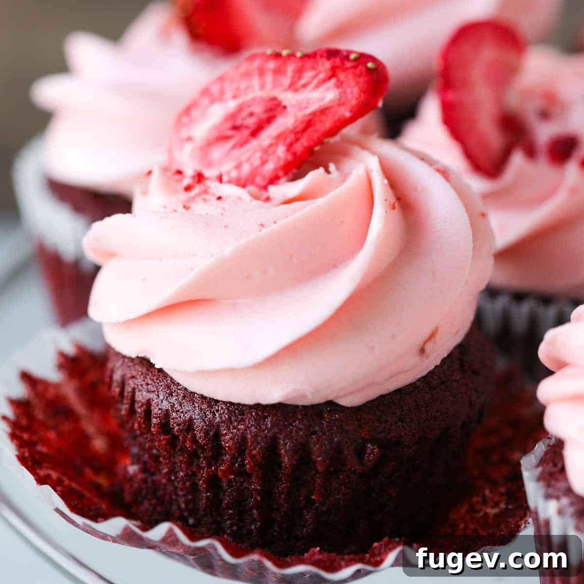 Lush Cream Cheese Buttercream 5 Strawberry cream cheese buttercream piped on a red velvet cupcake with a fresh strawberry on top.