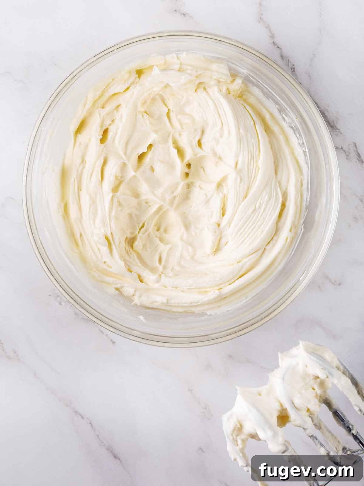Lush Cream Cheese Buttercream 6 Cream cheese buttercream frosting in a mixing bowl with beaters, showing its smooth consistency.