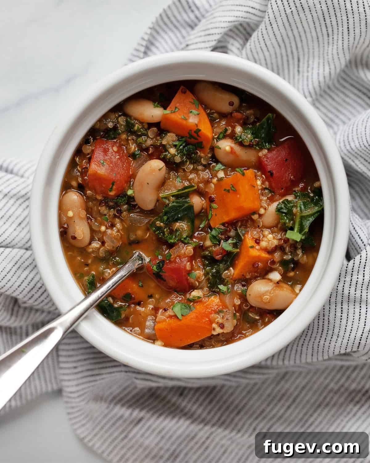 Sweet Potato White Bean Quinoa Bowl 2 A vibrant bowl of hearty sweet potato white bean quinoa soup, garnished with fresh herbs.
