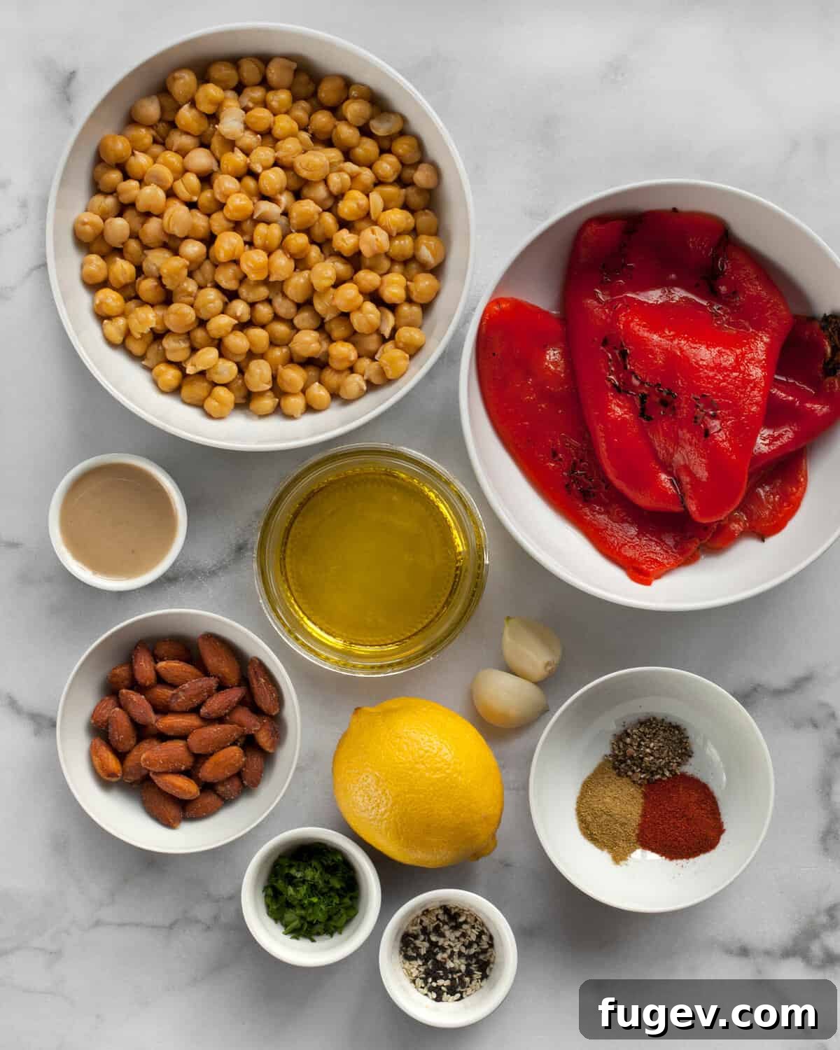 Flame-Kissed Red Pepper Hummus with Smoky Almond Crunch 3 A flat lay image showing all the ingredients for roasted red pepper hummus: chickpeas, roasted red peppers, smoked almonds, lemon, tahini, olive oil, garlic, cumin, smoked paprika, and black pepper.