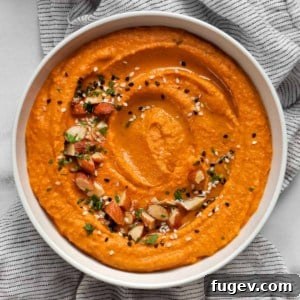 Flame-Kissed Red Pepper Hummus with Smoky Almond Crunch 7 Red pepper hummus garnished with chopped almonds, sesame seeds and parsley.