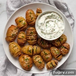Herby yogurt dip served alongside a plate of golden-brown mini hasselback potatoes.