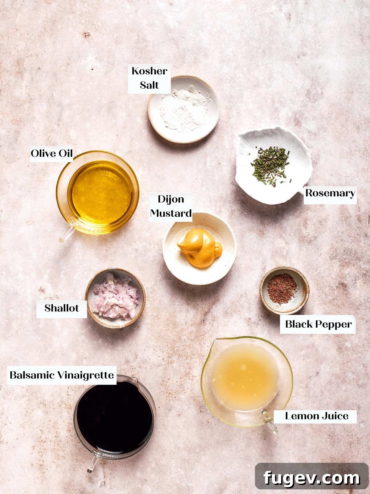 Key ingredients for lemon balsamic vinaigrette: balsamic vinegar, olive oil, fresh lemon, Dijon mustard, and shallot, arranged on a kitchen counter.