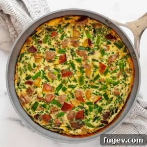Roasted asparagus frittata, golden and bubbly, in a cast-iron skillet, ready for serving.