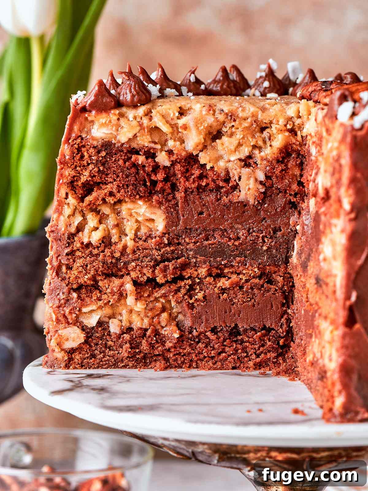 Decadent German Chocolate Cake 2 German chocolate cake displayed on a marble cake stand with rustic topping and a beautiful presentation.