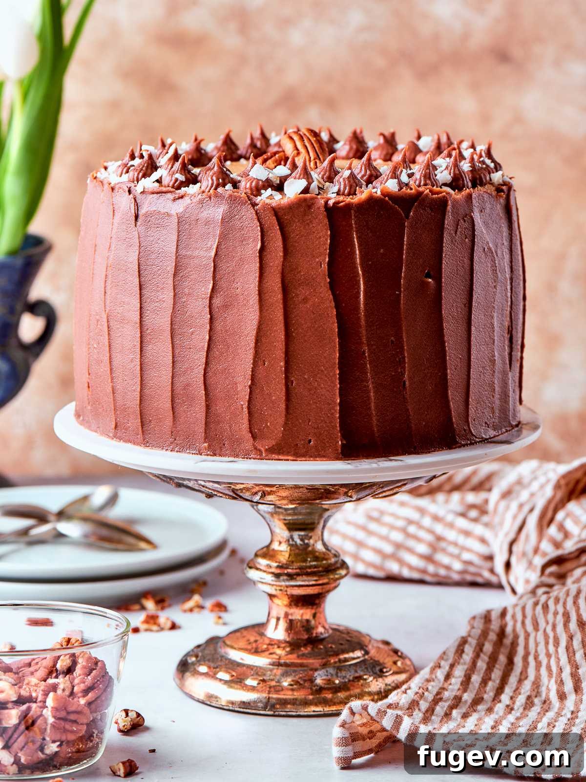 Decadent German Chocolate Cake 26 A whole German chocolate cake, beautifully topped with a generous mound of coconut pecan frosting and stacked layers visible from the side.