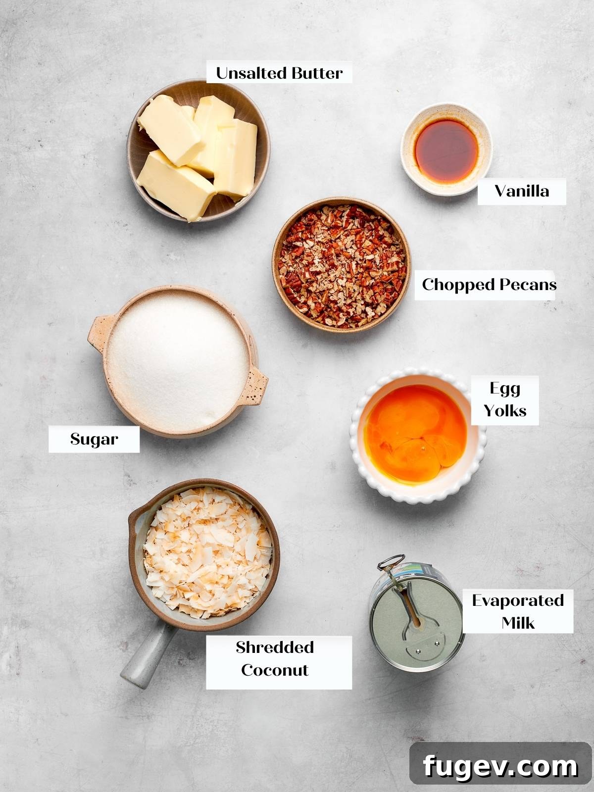 Decadent German Chocolate Cake 5 German chocolate cake topping ingredients, including shredded coconut and chopped pecans, arranged on a white countertop.