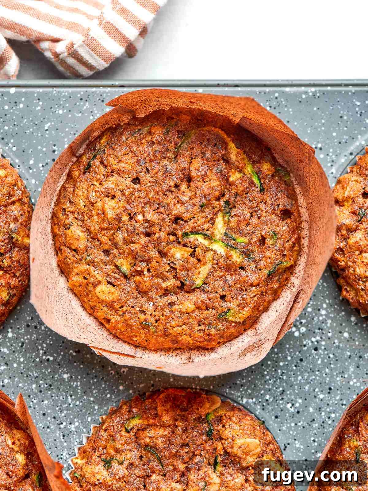 A batch of freshly baked zucchini muffins, showcasing their golden-brown tops, lightly set edges, and inviting texture straight out of the oven.