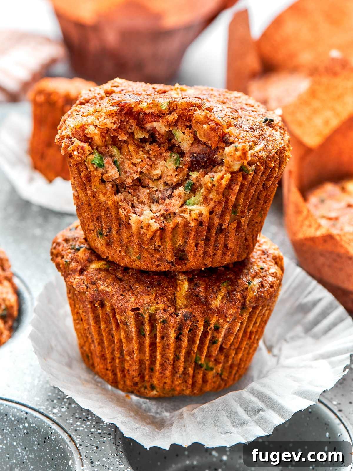 A beautiful stack of golden-topped zucchini muffins, revealing their tender crumb and wholesome ingredients, ready to be enjoyed.