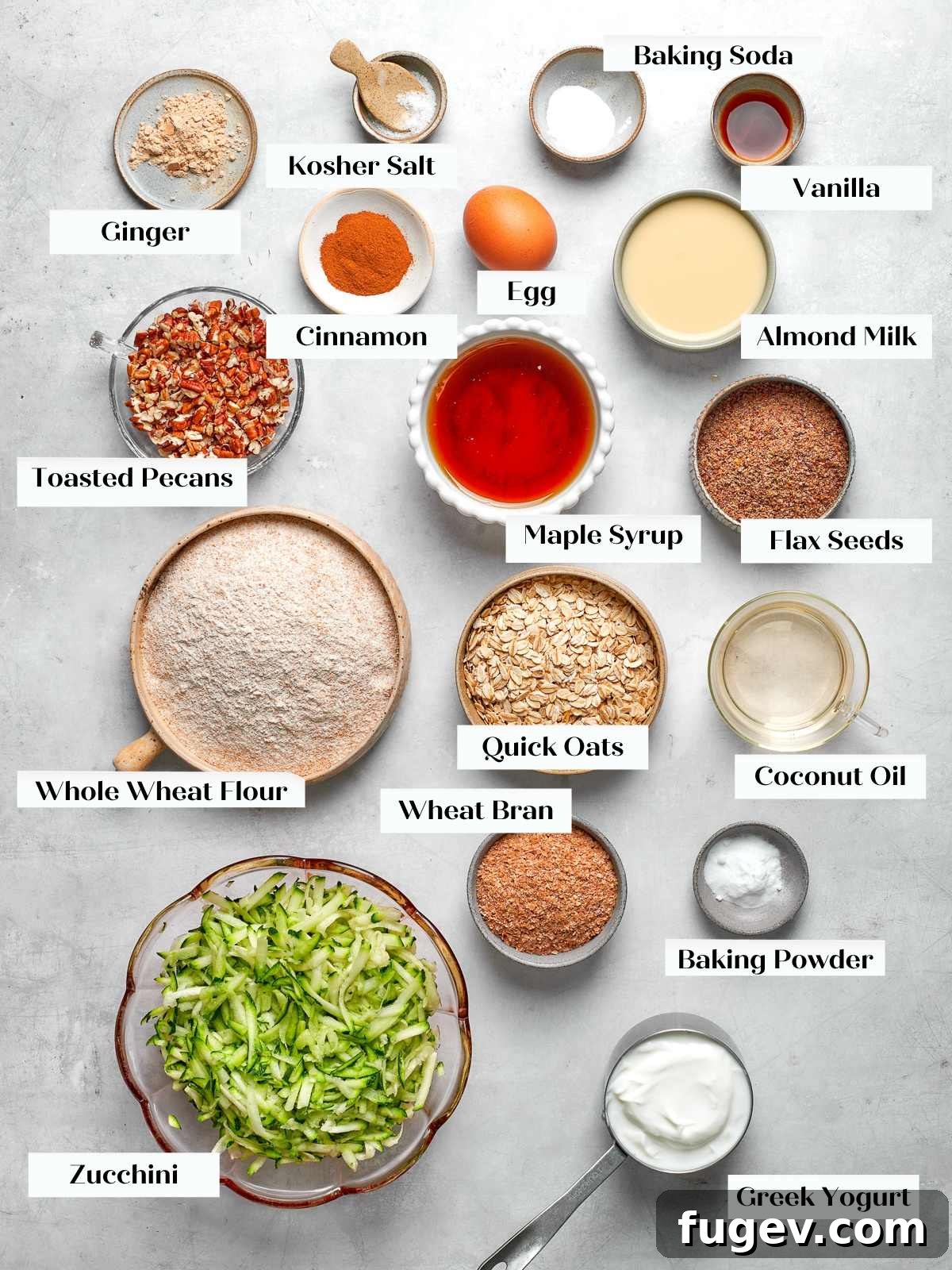 Ingredients for healthy and moist zucchini muffins, including whole wheat flour, oats, Greek yogurt, and freshly shredded zucchini, laid out on a kitchen counter.