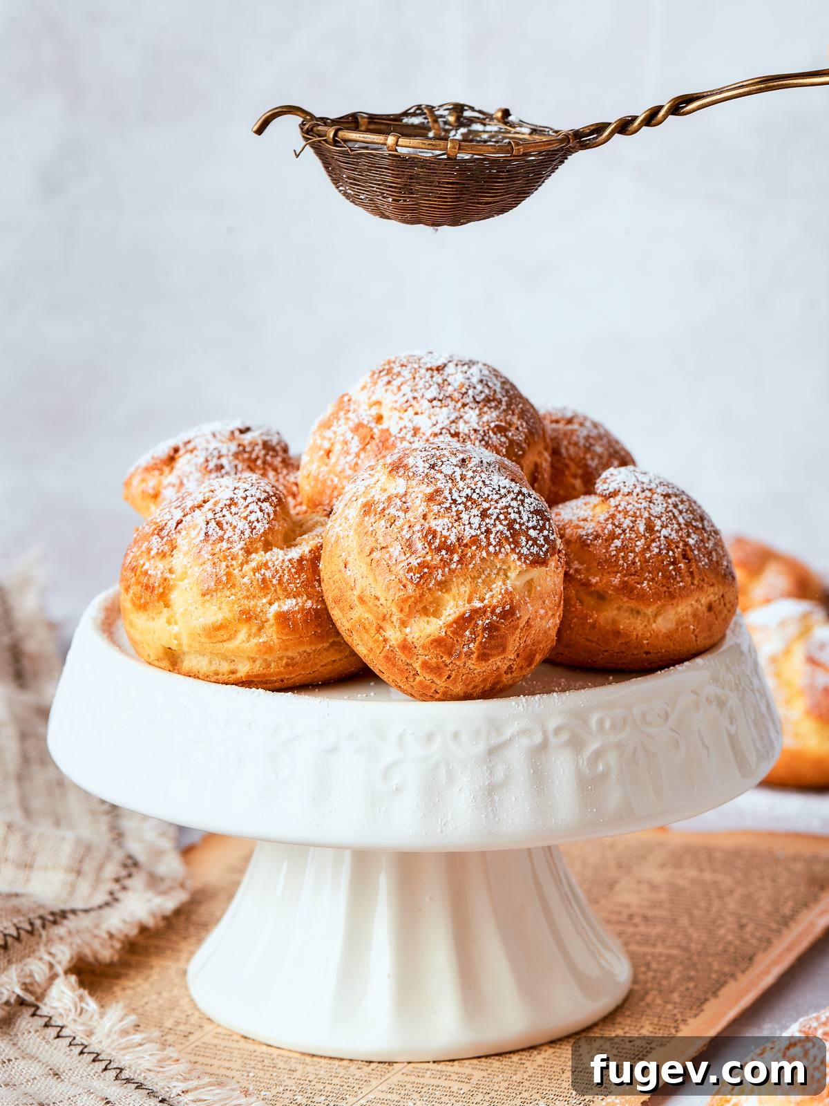 Sweet Cream Clouds 2 Finished cream puffs dusted generously with powdered sugar for classic bakery-style presentation, showcasing their golden-brown perfection.