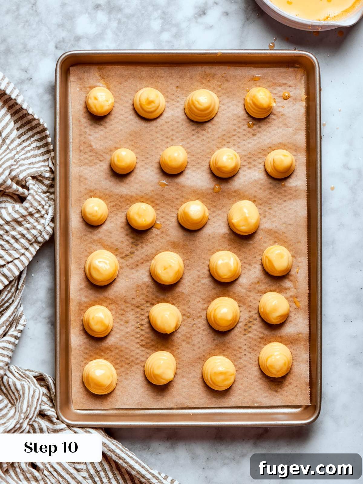 Sweet Cream Clouds 24 Piped choux pastry rounds egg washed, ready for baking to achieve a glossy finish.