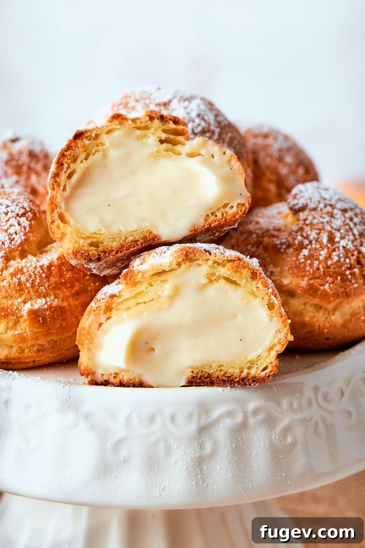 Sweet Cream Clouds 35 Filled cream puffs displayed on cake stand with light dusting of powdered sugar, ready to be served.