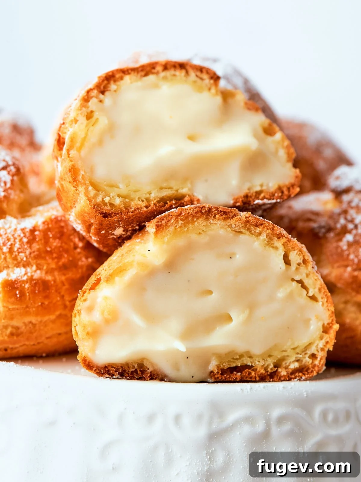 Split cream puffs revealing airy crème légère filling inside crisp pastry shells.