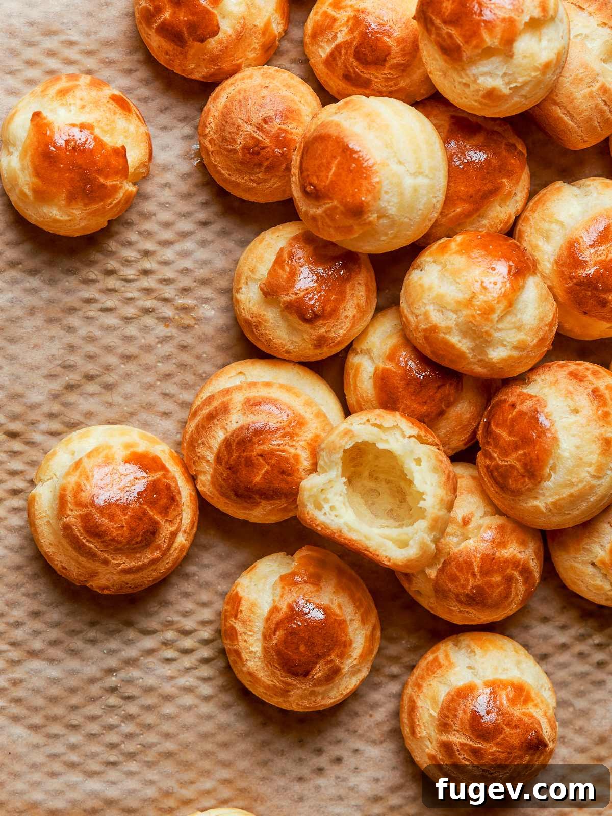 Tray of perfectly baked golden-brown choux pastries, consistently puffed and evenly crisp.