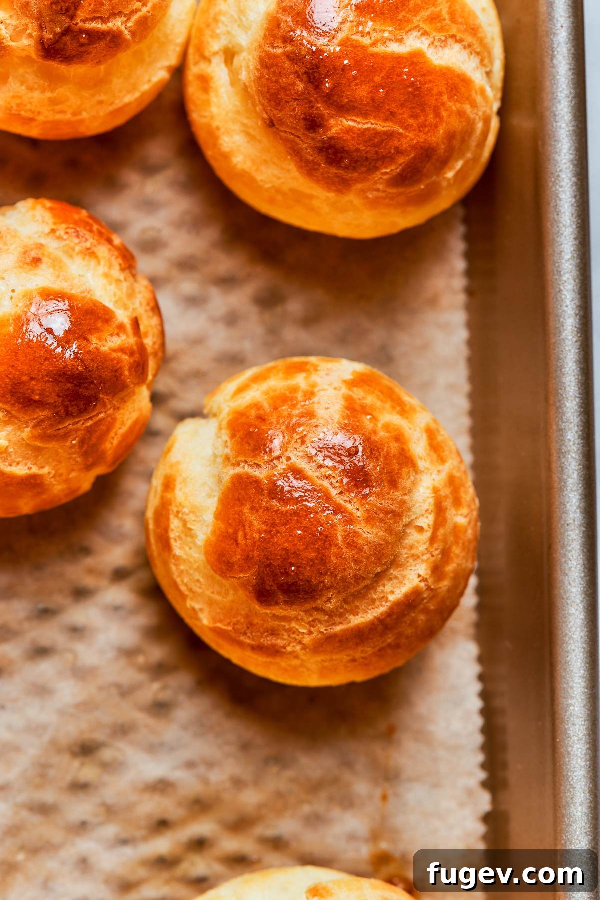 A single perfectly golden-brown choux pastry puff, showcasing its even browning and a well-developed, crisp shell, ready to be filled.