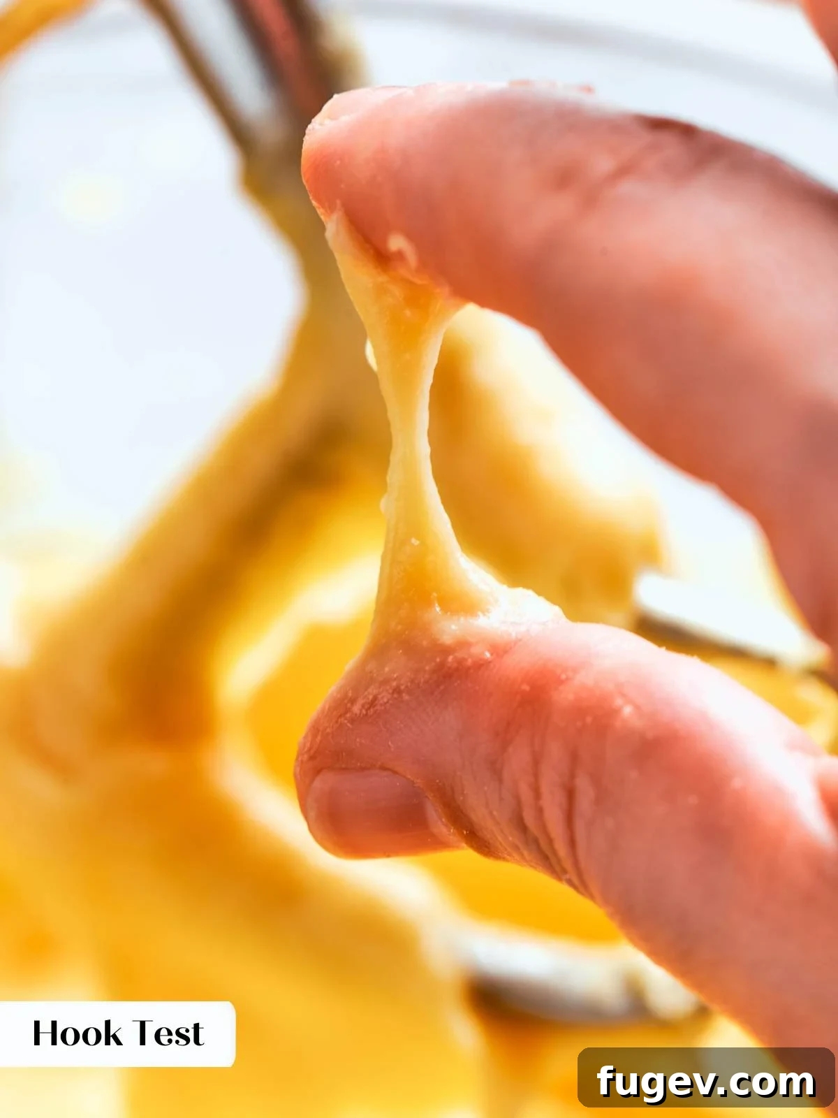 The hook consistency test being performed on choux pastry dough, showing the characteristic soft peak flopping to the side.