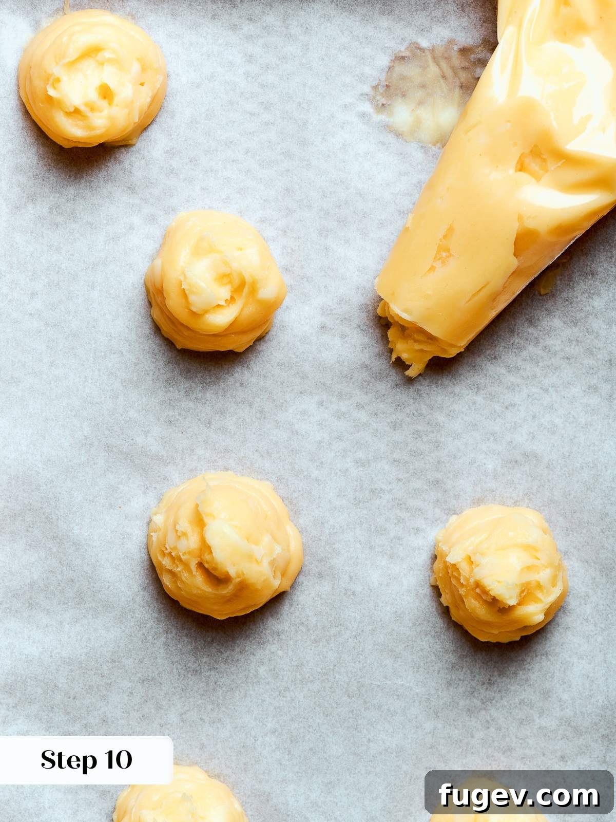 Golden Savory Puffs 18 Choux dough piped into small rounds on parchment with consistent spacing between each. A baking sheet filled with perfectly piped Gougères.