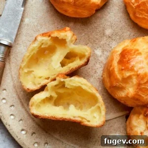 Interior of gougère showing large hollow pocket and delicate airy crumb structure. A cross-section of a Gougère revealing its ideal texture.