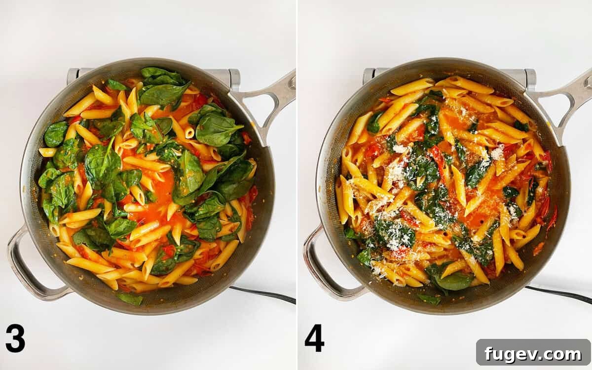 Baby spinach folded into tomato pasta in a skillet. Pasta sprinkled with grated parmesan and fresh herbs.