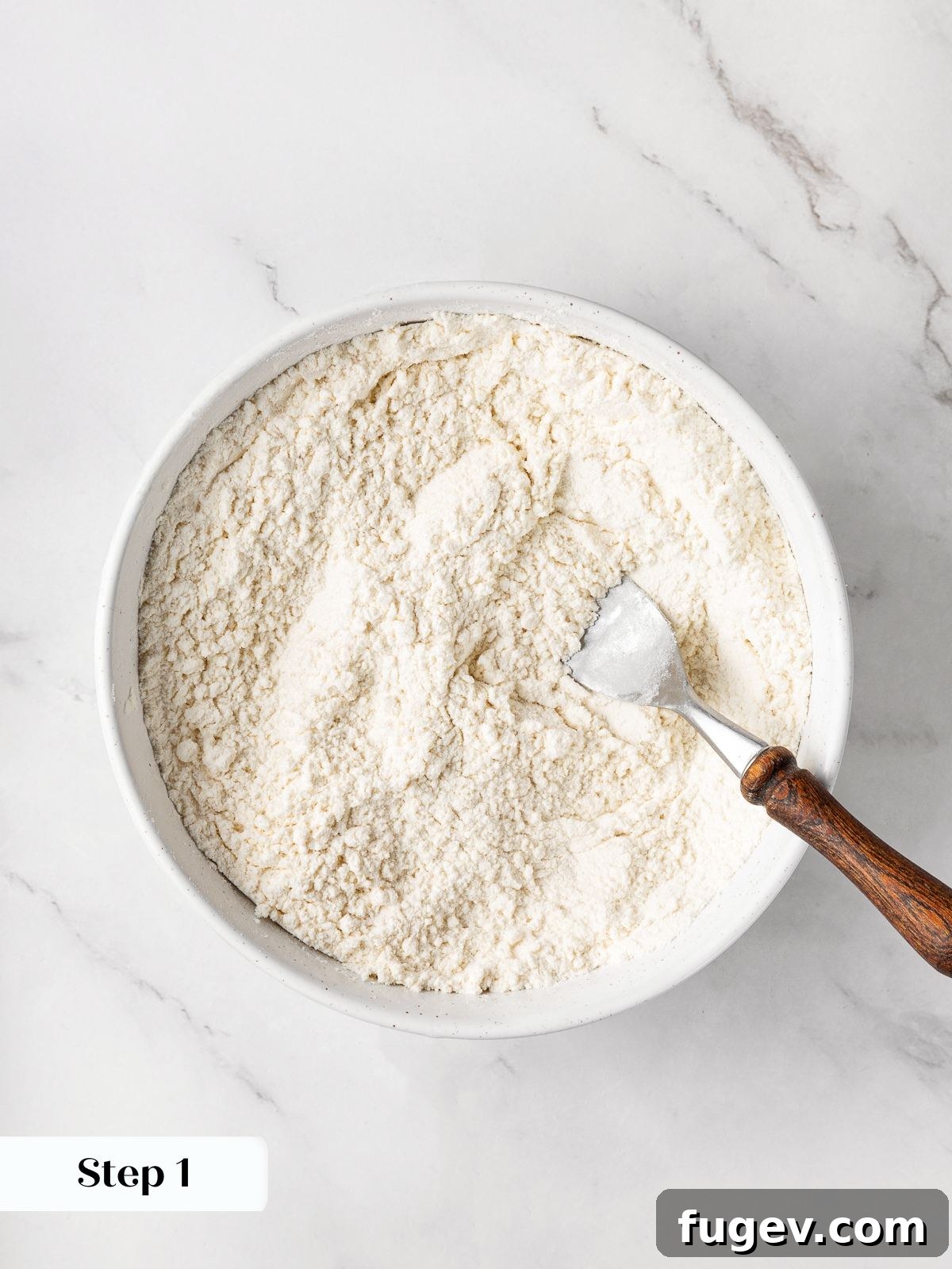 A bowl containing the mixed dry ingredients: flour, salt, and leaveners.