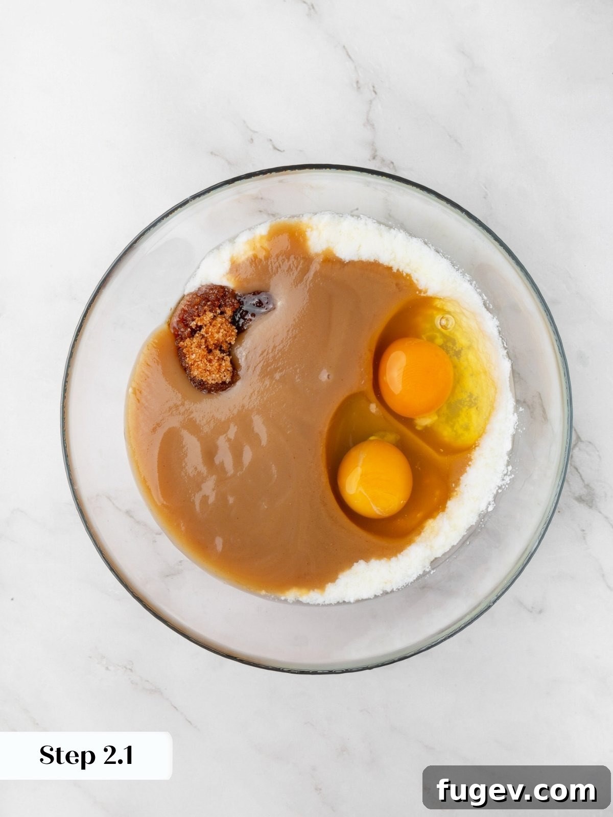 Eggs, applesauce, and brown sugar pooled together in a glass bowl ringed with granulated sugar.