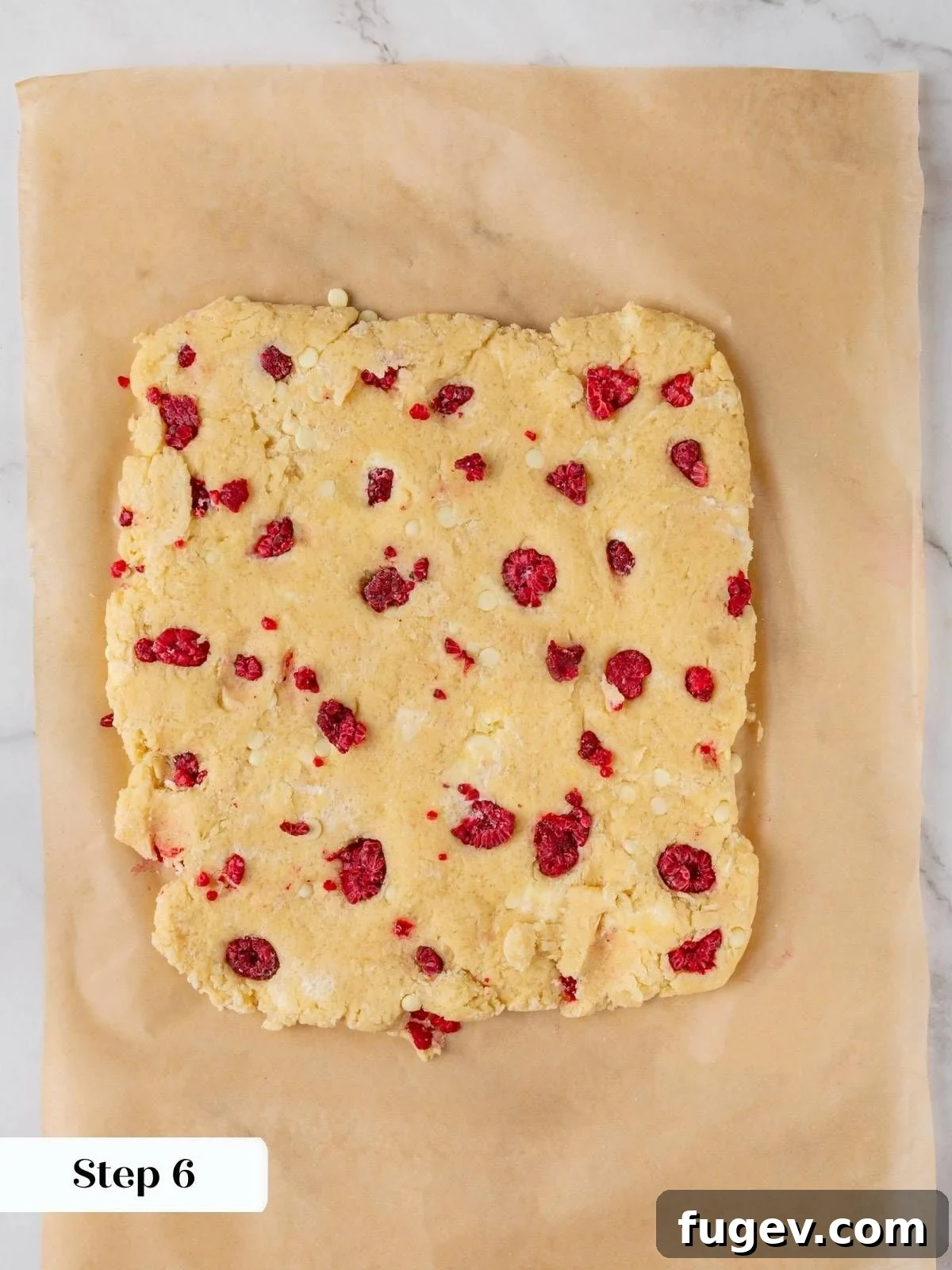 White Chocolate Raspberry Bliss Scones 14 Scone dough being pressed into a uniform square shape on parchment paper.