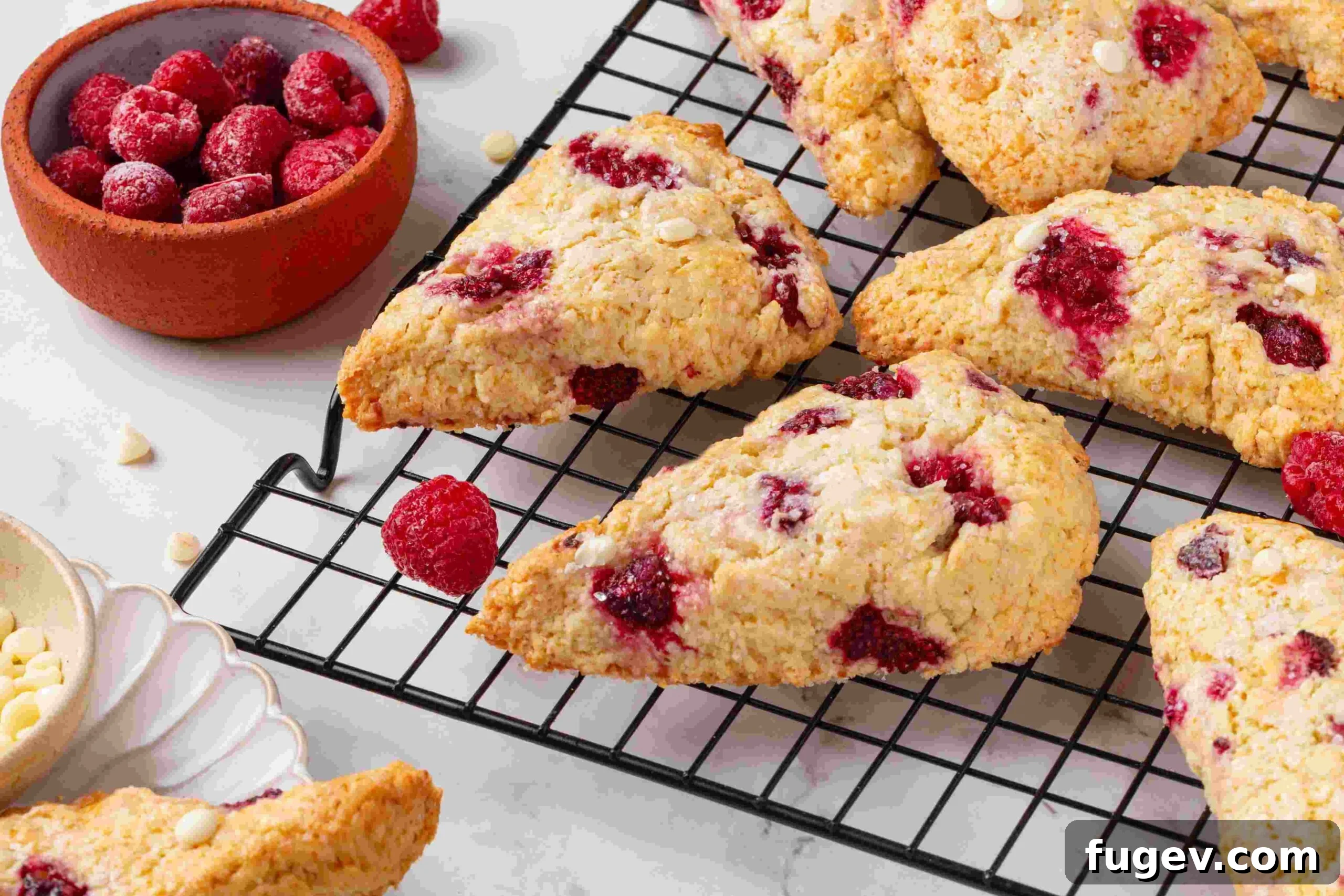 White Chocolate Raspberry Bliss Scones 5 A side view of raspberry white chocolate scones on a wire rack, showcasing their height and golden texture.