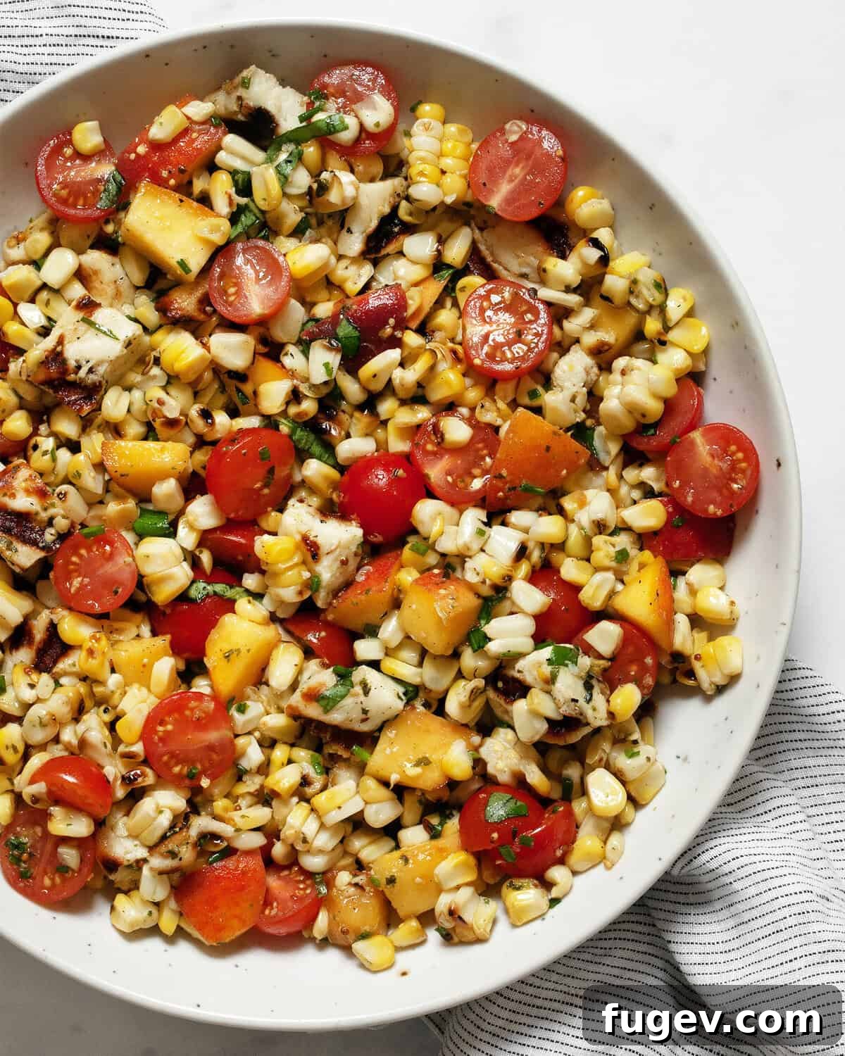 Grilled halloumi salad with corn, tomatoes and peaches in a bowl.
