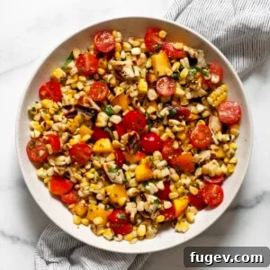 Grilled halloumi salad with corn, tomatoes and peaches in a bowl.