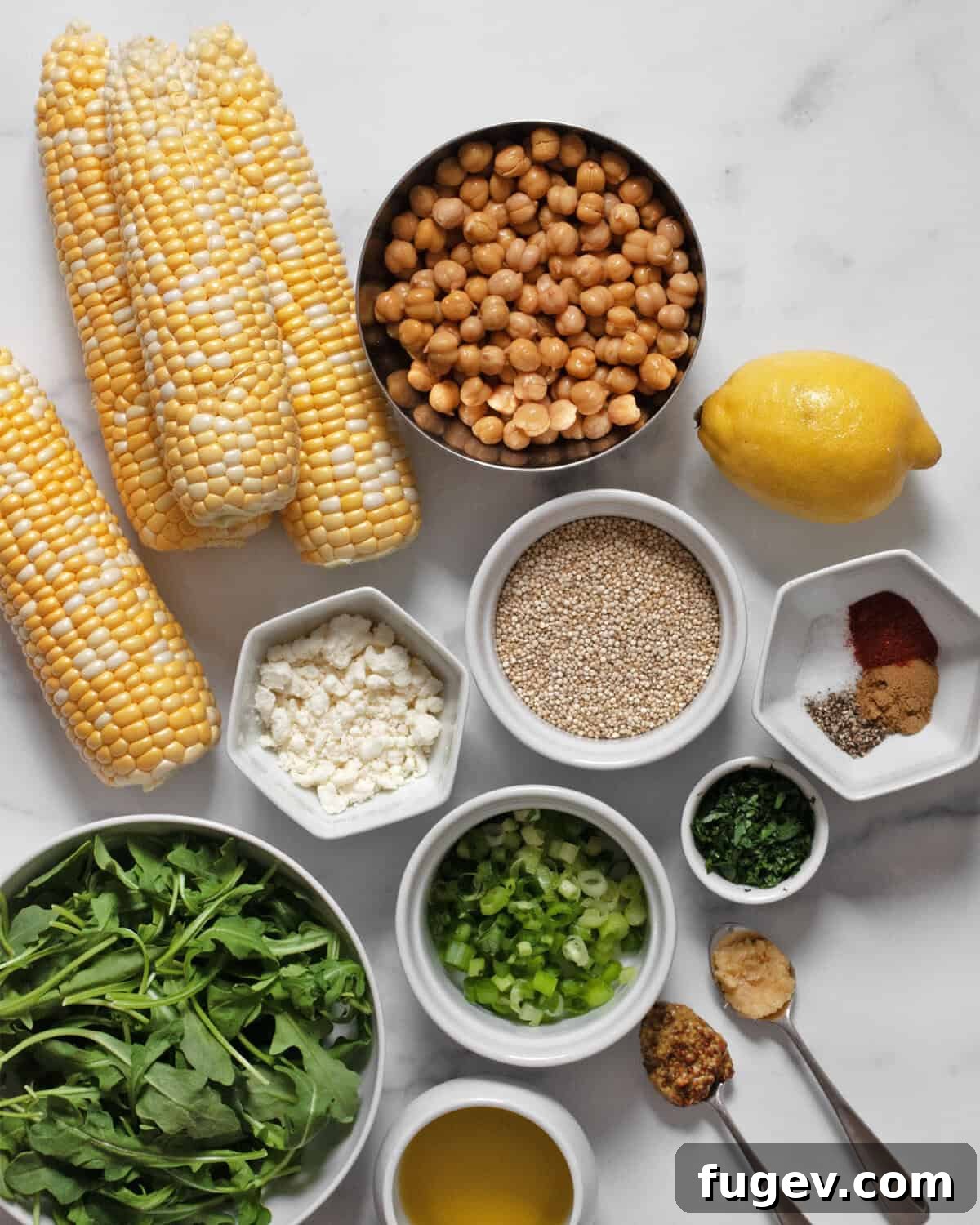 Ingredients including corn, chickpeas, arugula, quinoa, feta, parsley, lemon, garlic, mustard, spices and olive oil.